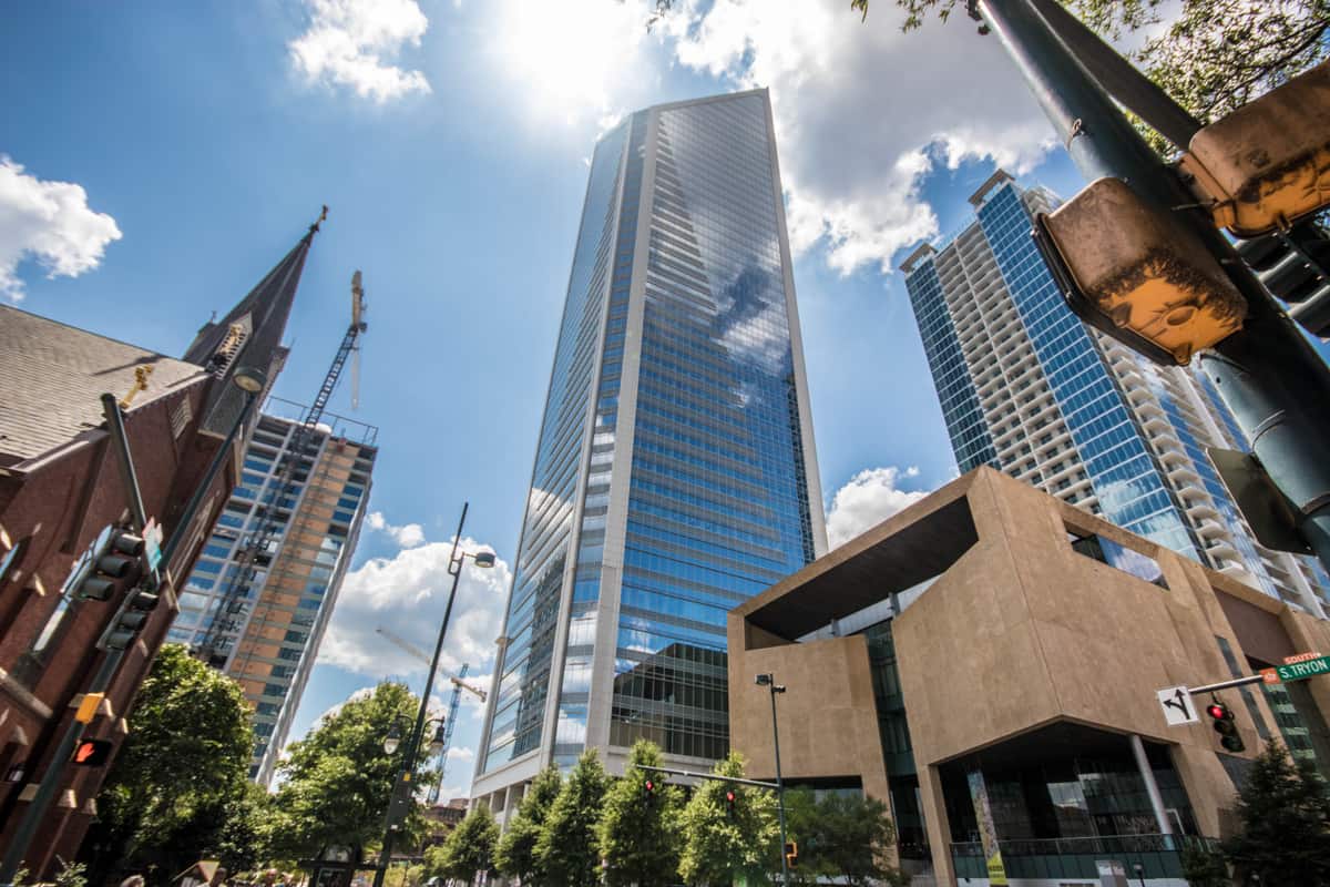 Duke Energy Center rising above South Tryon Street in uptown Charlotte, North Carolina, with the Bechtler Museum of Modern Art at right and construction cranes working over a tower going up nearby